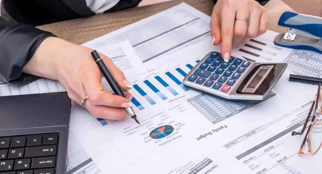 Business woman account annual budget with laptop, pen and graph